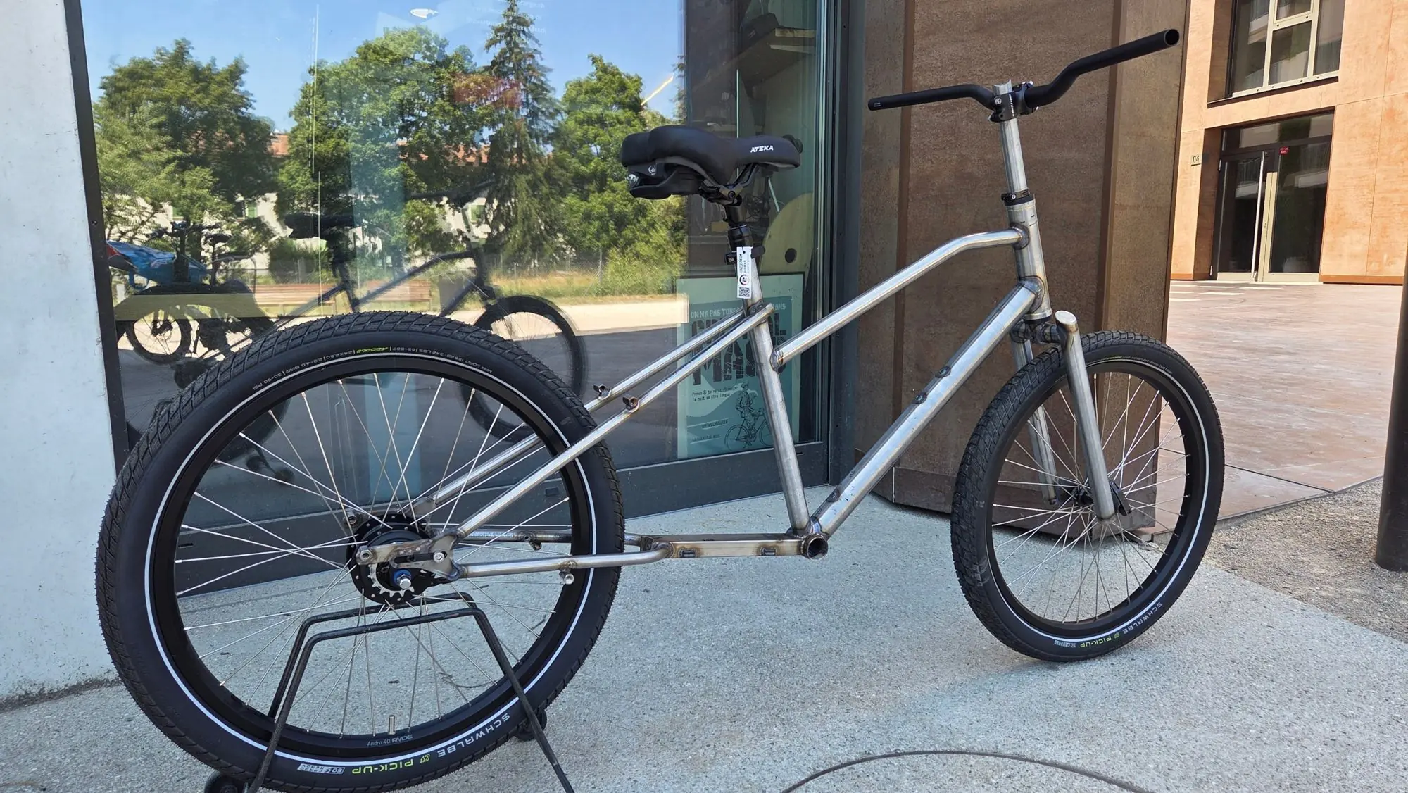 Cadre de vélo cargo en acier brut, sans peinture, devant l’atelier
