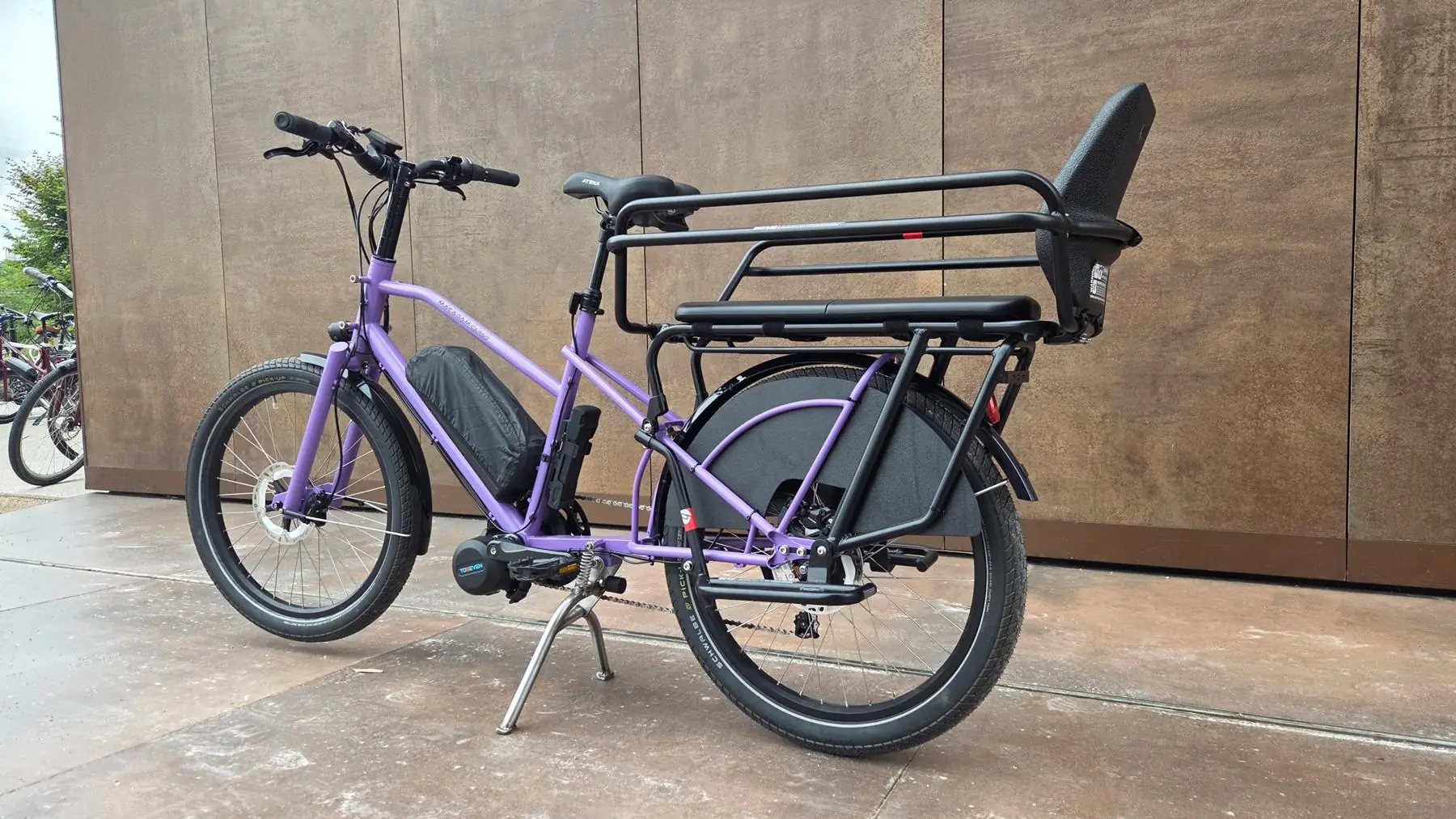 Le longtail violet vu de trois quarts arrière avec son porte-bagage et son siège enfant