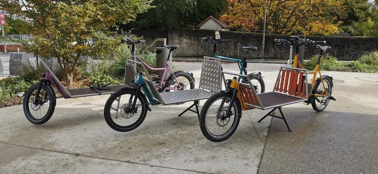 Trois vélos cargo Macadam Cargo colorés devant des arbres d’automne