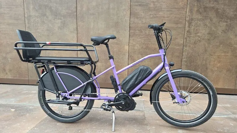 Le longtail, vélo cargo violet avec banquette et porte-bagages à l’arrière