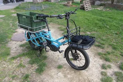 Longtail bleu avec une caisse de transport fixée sur sa plateforme en Inox