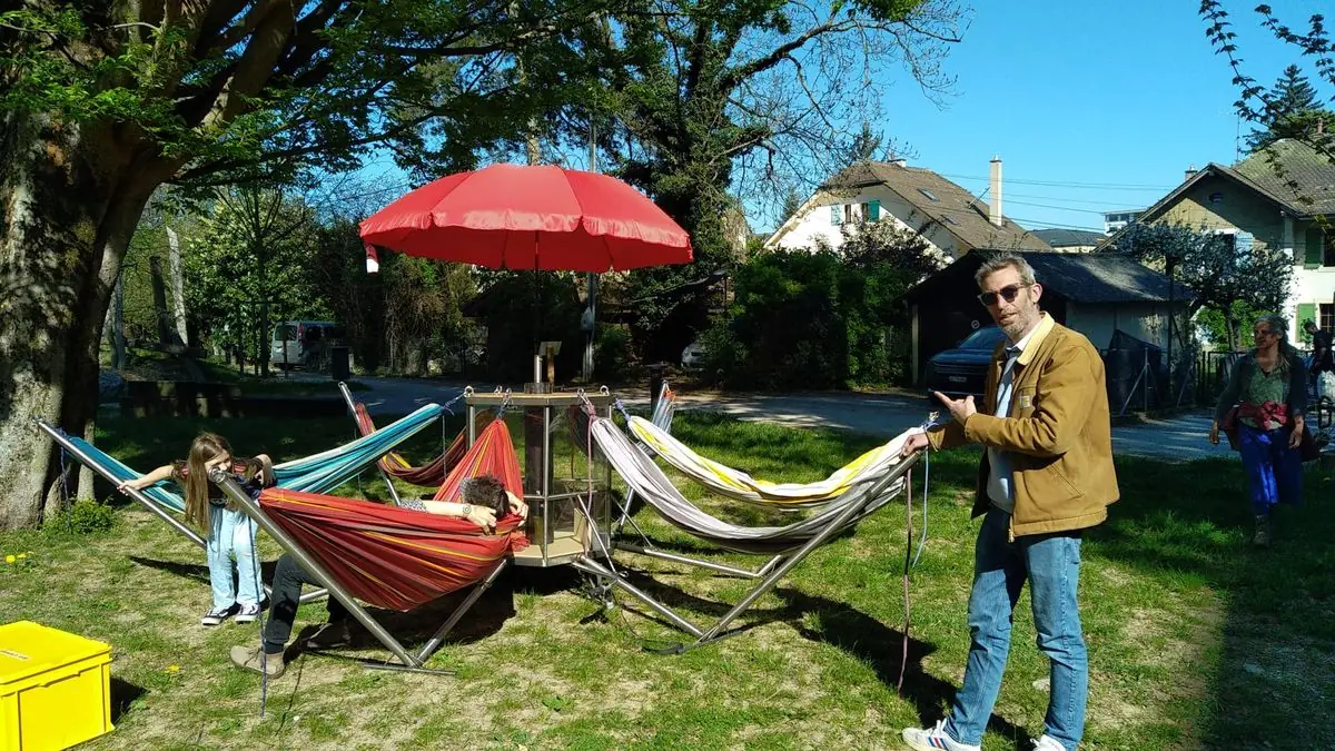 Hamacs installés autour d’une structure en Inox dans un parc, sous un parasol rouge